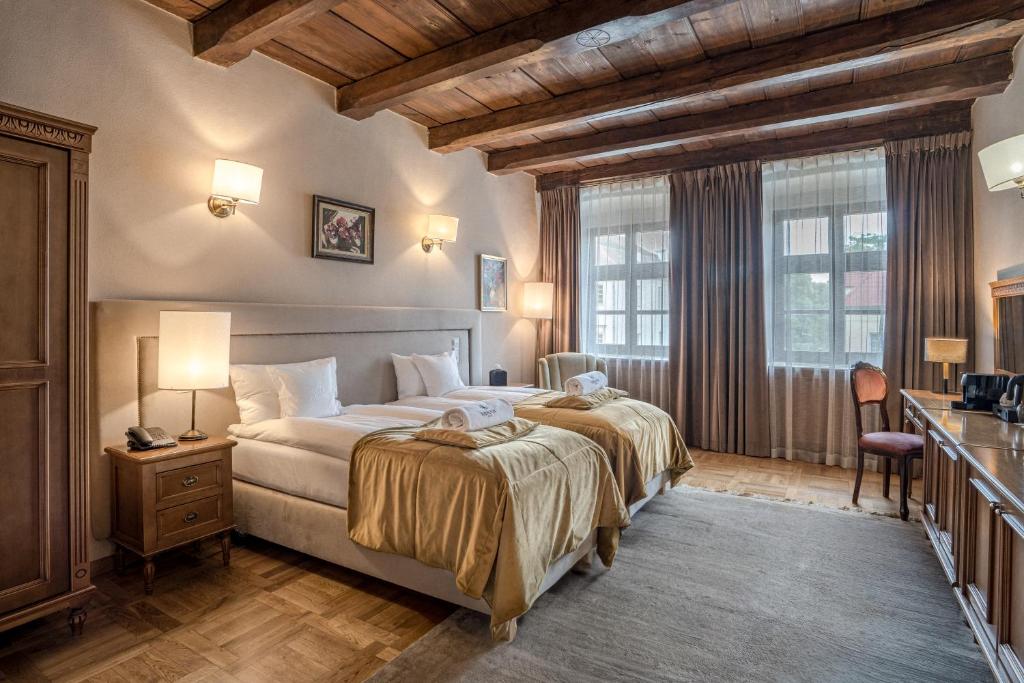 a bedroom with a large bed and two windows at Hotel Rubinstein in Krakow
