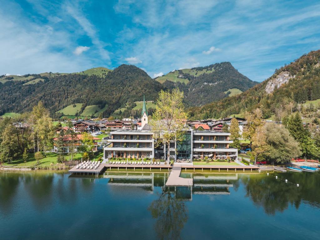a resort on a lake with mountains in the background at Das Lakeside - Move&Relax in Walchsee