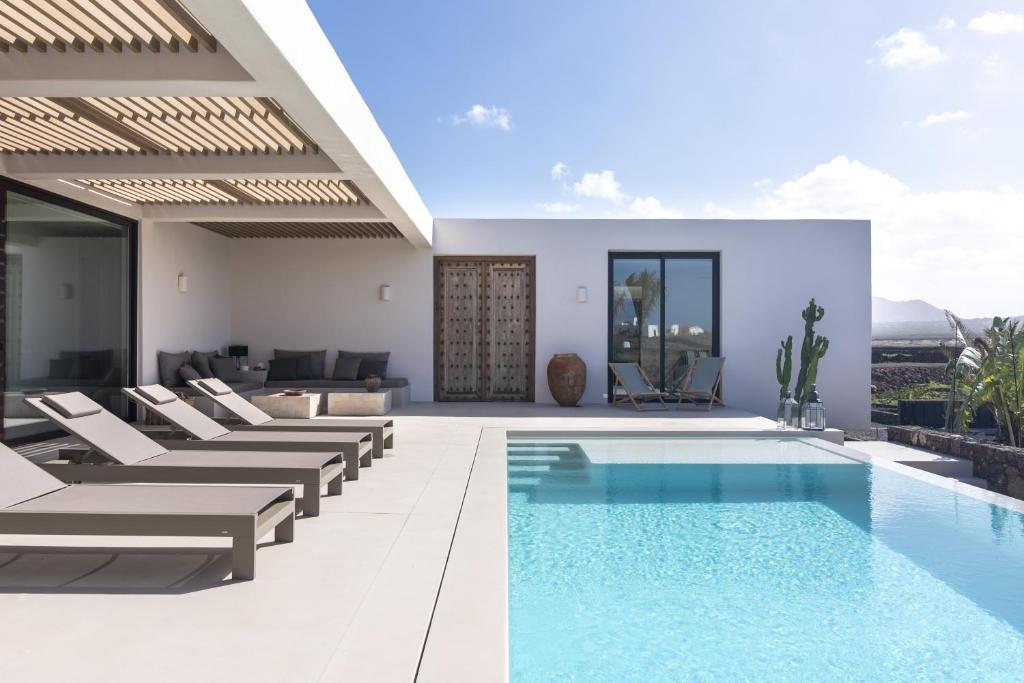 a villa with a swimming pool and lounge chairs at Villa Gara exclusive luxury villa with heated pool in Lajares
