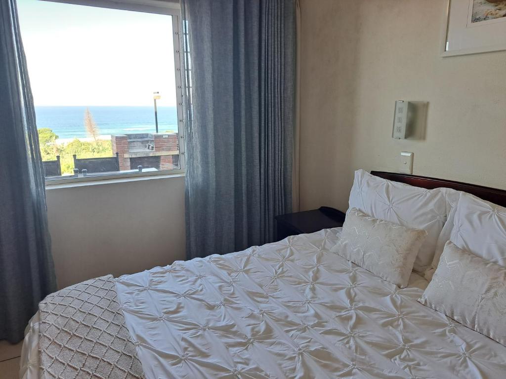 a bedroom with a white bed and a window at #7 Illovo Views in Kingsborough