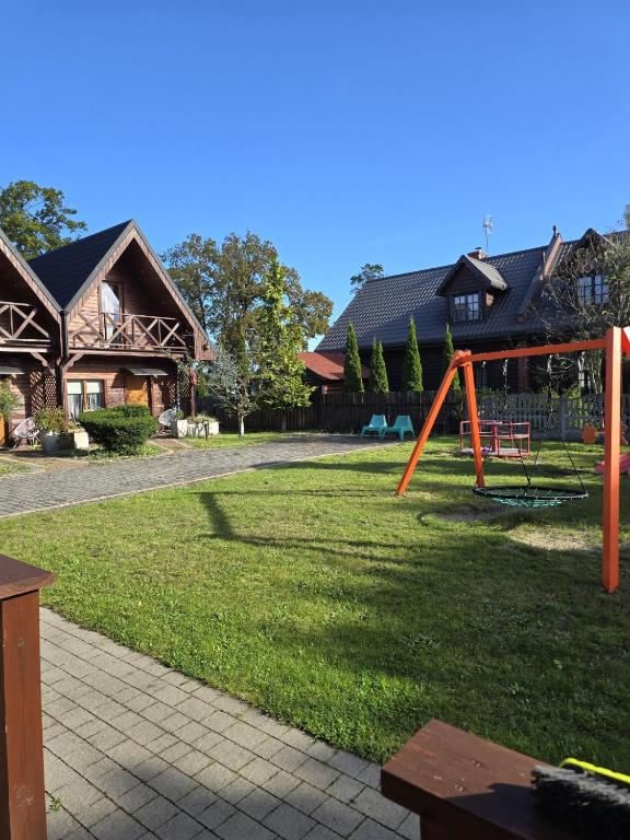 a playground in a yard with a house at Domki Relaksowa in Nowęcin