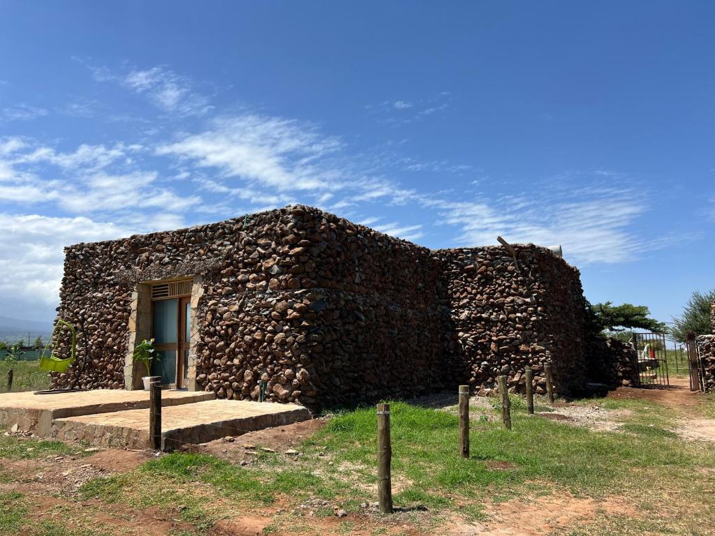 a stone building with a door in a field at I love Amboseli in Kimana