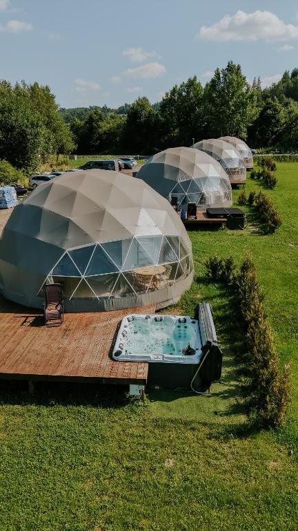 a group of domes on a deck with a hot tub at Aqua Glamp in Jaszczurowa