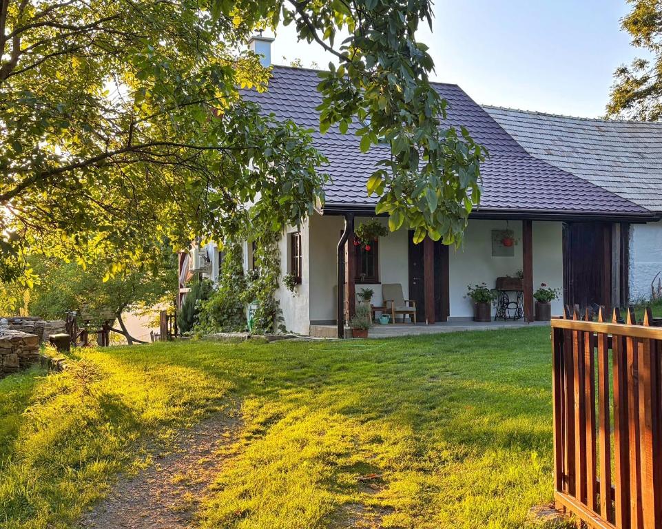 a white house with a fence in the yard at Chalúpka Polom in Hnúšťa