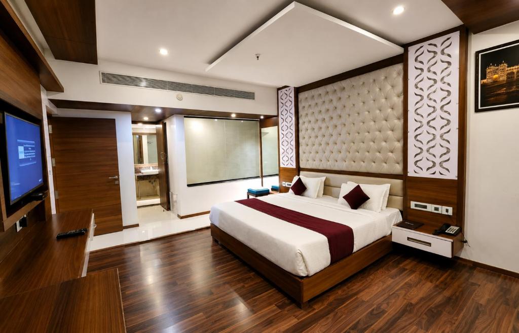 a bedroom with a bed and a flat screen tv at Hotel Preethi International in Mysore