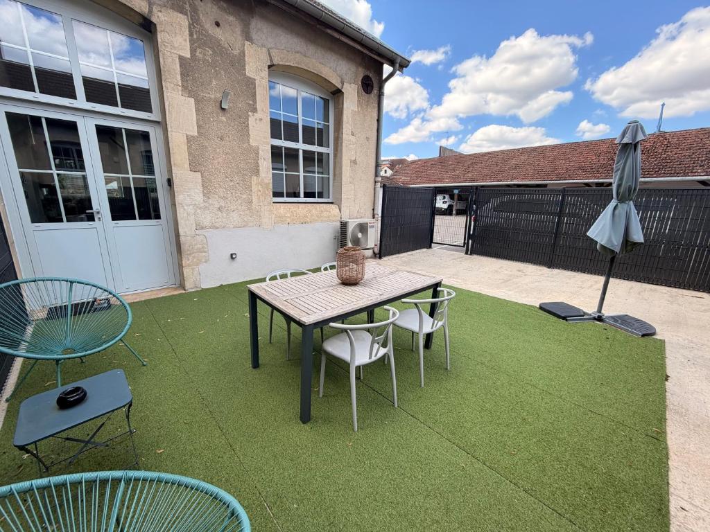 a patio with a table and chairs and an umbrella at Le Côté Cour in Dole