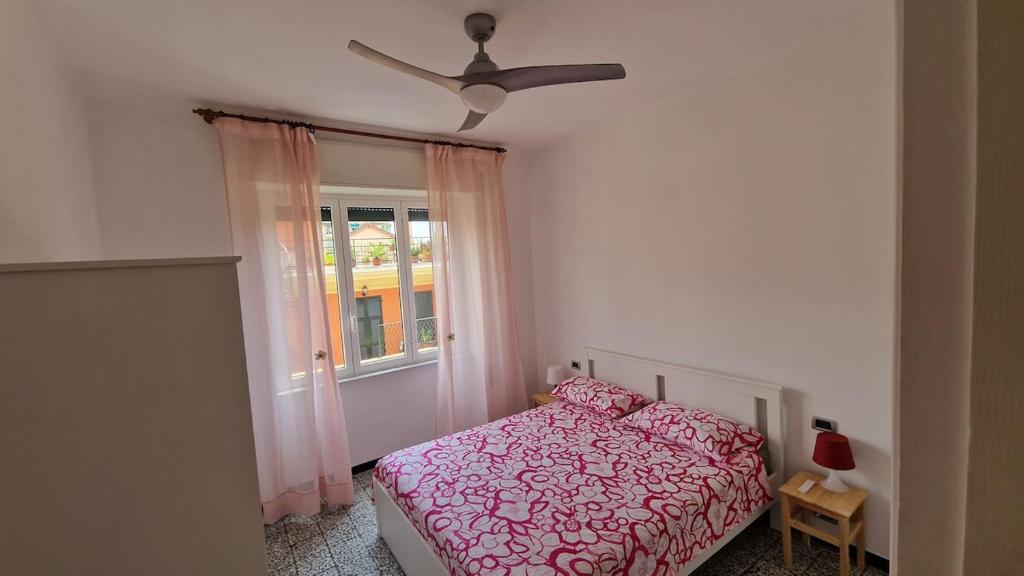 ein Schlafzimmer mit einem rosa Bett und einem Fenster in der Unterkunft Rapallo Riviera in Rapallo