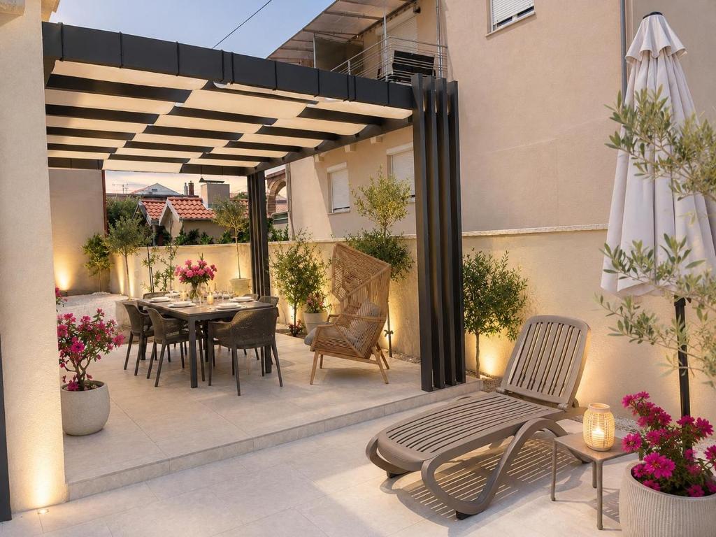 a patio with a table and chairs and an umbrella at Luxury Villa Olga in Biograd na Moru