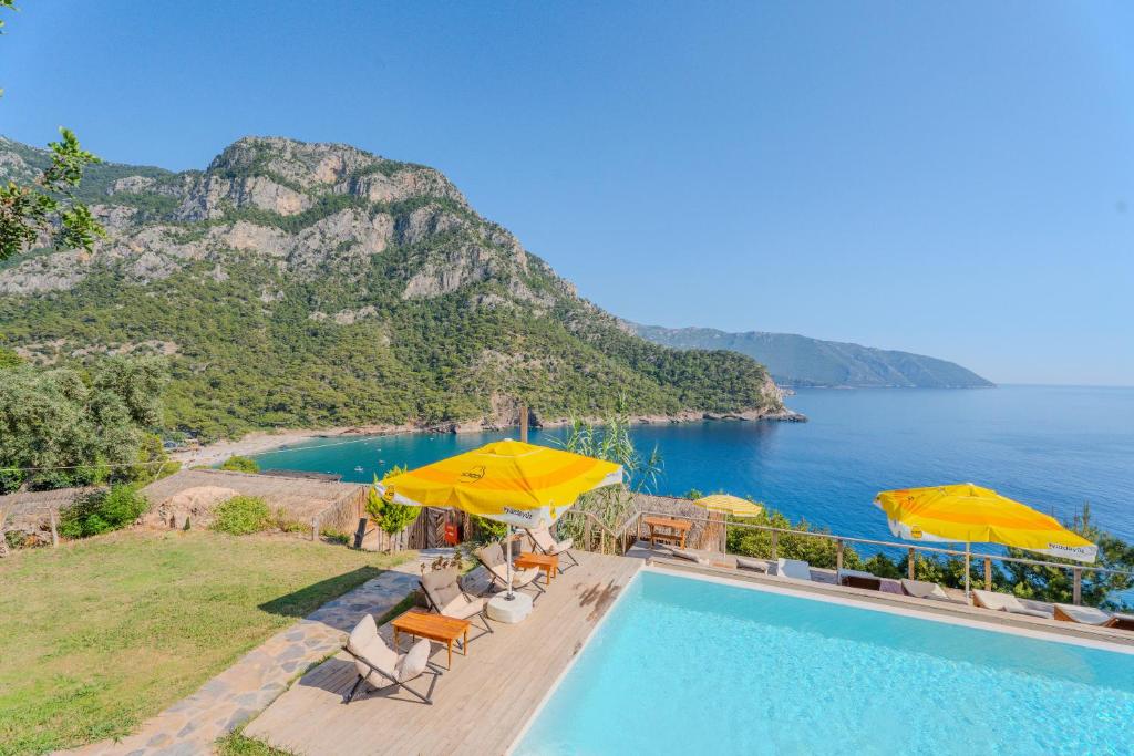 ein Schwimmbad mit gelben Sonnenschirmen und das Meer in der Unterkunft Flavia Hotel in Kızılcakaya