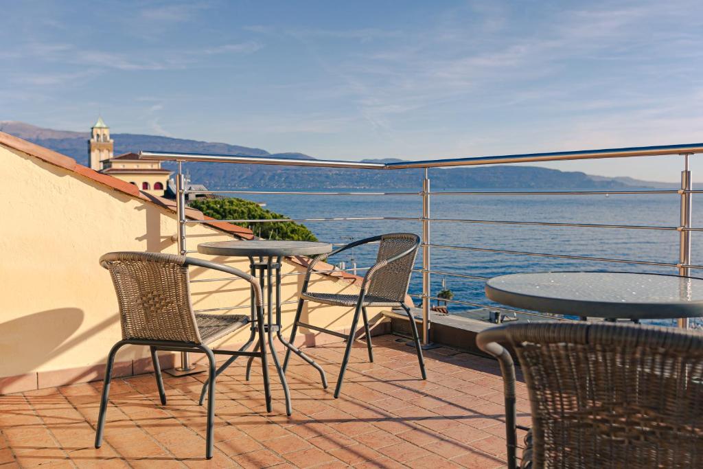 a balcony with tables and chairs and a view of the water at Magnifica Terrazza - Lake View & Wi-Fi in Gardone Riviera