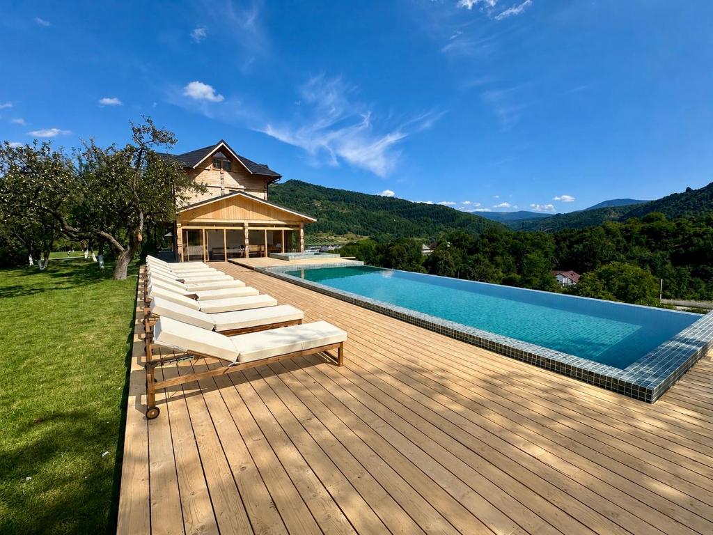 a wooden deck with a swimming pool and a house at Pensiunea Coronita in Vişeu de Sus