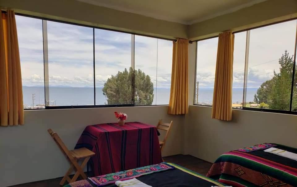 a bedroom with a table and chairs and large windows at Kusk'a Lodge in Puno