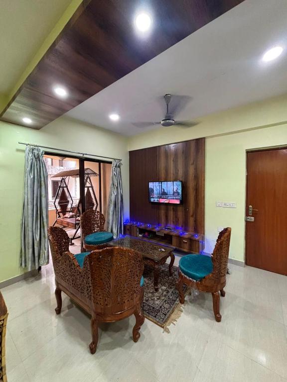 a living room with a table and chairs and a tv at The Humble Abode in kolkata