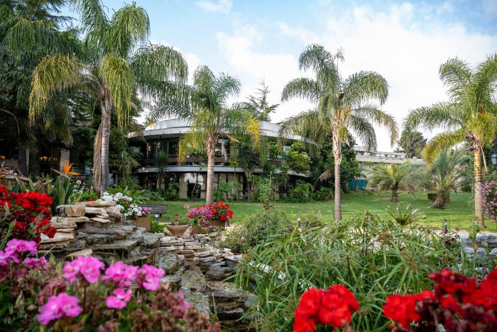a house with palm trees and a garden with flowers at Hacienda Forest View Hotel in Ma'alot Tarshiha