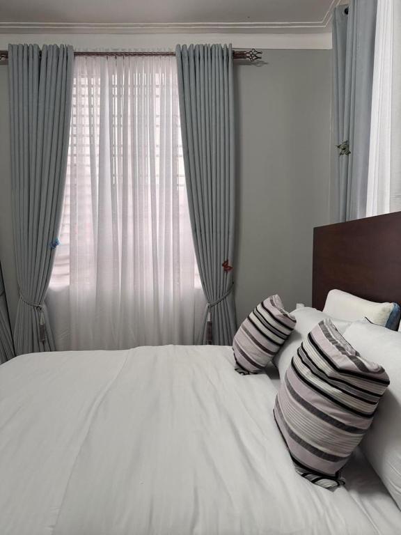 a bedroom with a white bed with pillows and a window at Ssentongo Properties Limited in Kampala