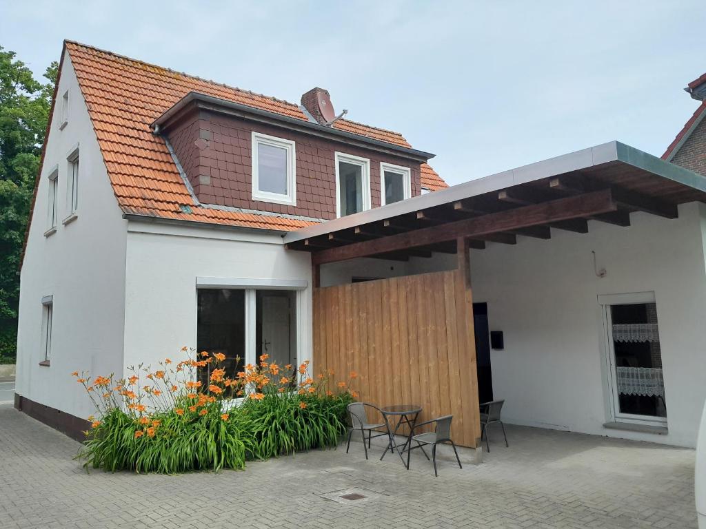 a white house with chairs and flowers on a patio at Carodorfblick in Carolinensiel