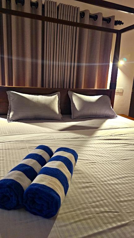 a bed with two blue and white pillows on it at Samson & Ruby Villa in Weligama