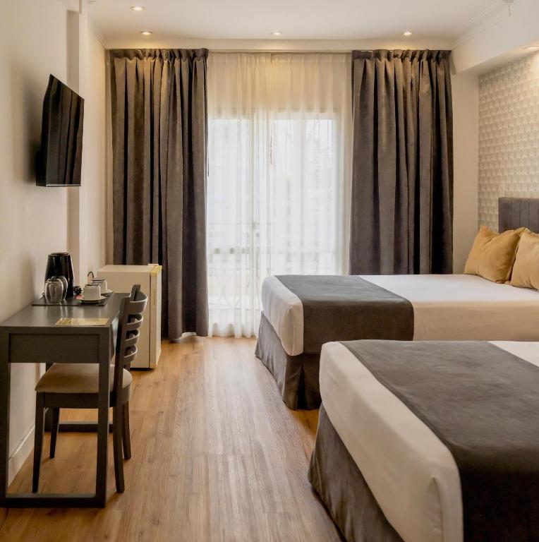 a hotel room with two beds and a desk at Hotel Copahue in Junín