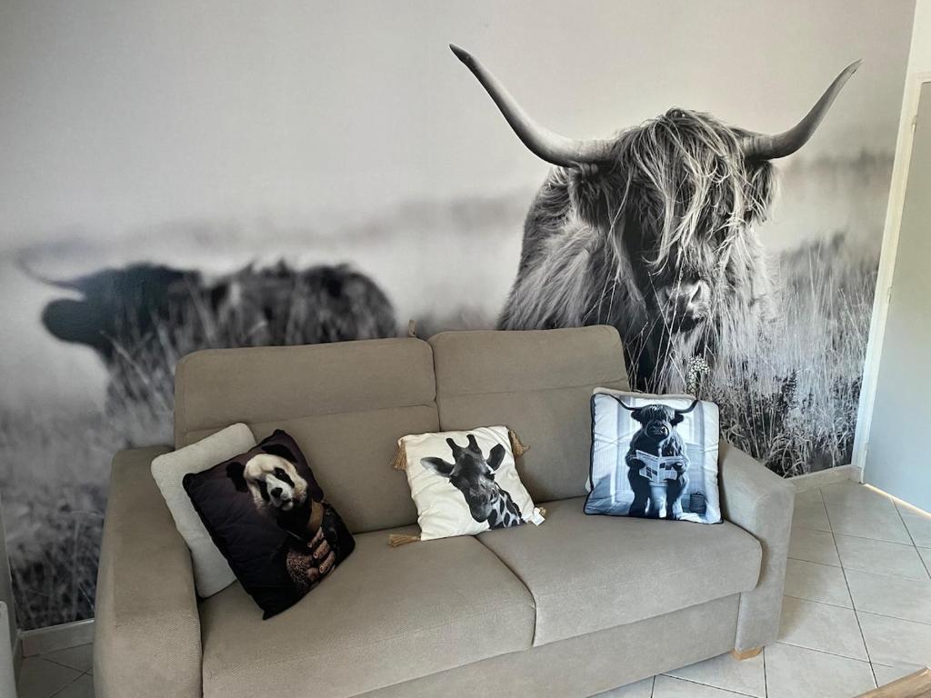 a couch in a living room with a cow mural at Gîte du Trefoux logement Le Perche in Villaines-la-Gonais