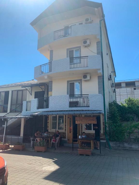 a tall white building with people sitting outside of it at Cactus Hotel in Kobuleti