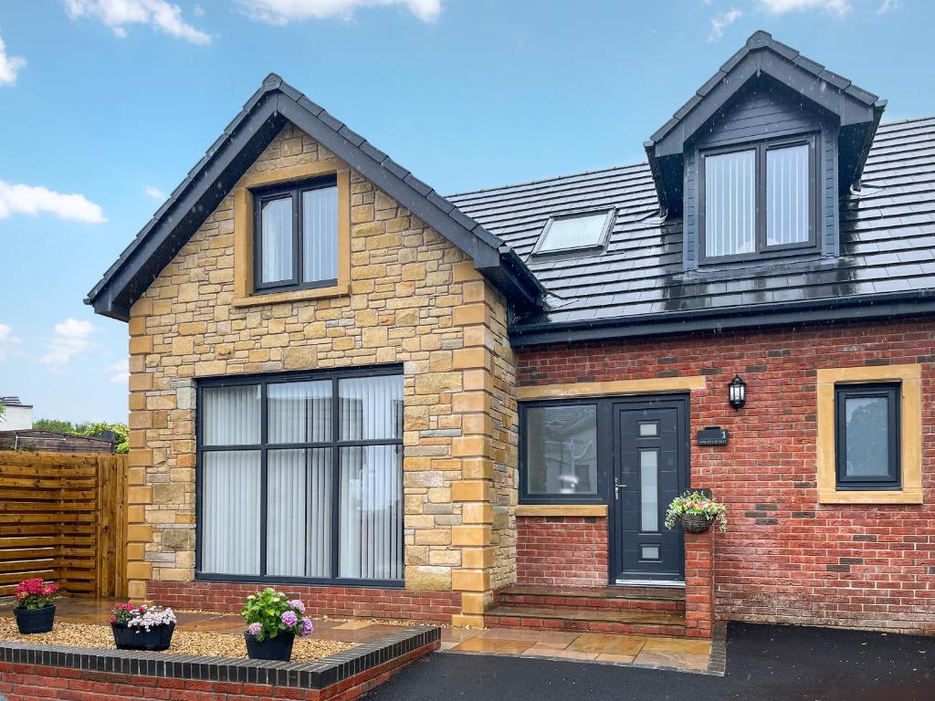 a red brick house with black doors and windows at Barncroft Retreat - Uk51693 in Flimby