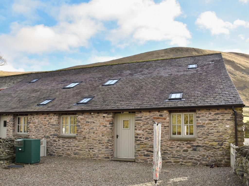 a stone house with a roof with windows at Combe Cottage-Uk42228 in Low Borrowbridge