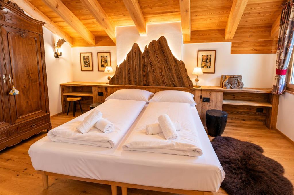 a large white bed in a room with wooden ceilings at Chalet degli Abeti by AMA Val di Fassa in Campitello di Fassa