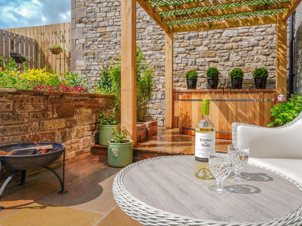 a table with a bottle of wine on a patio at Westhills Courtyard - The Loft in Winster