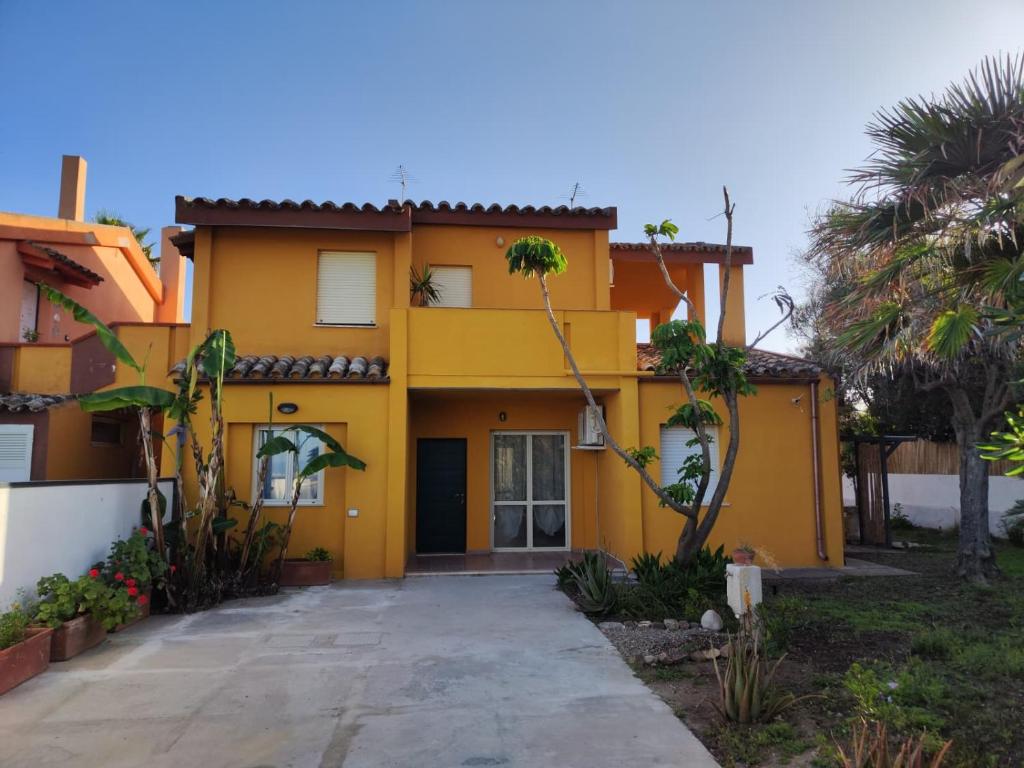 a yellow house with palm trees in front of it at Oasi Villa Giusy in Capoterra