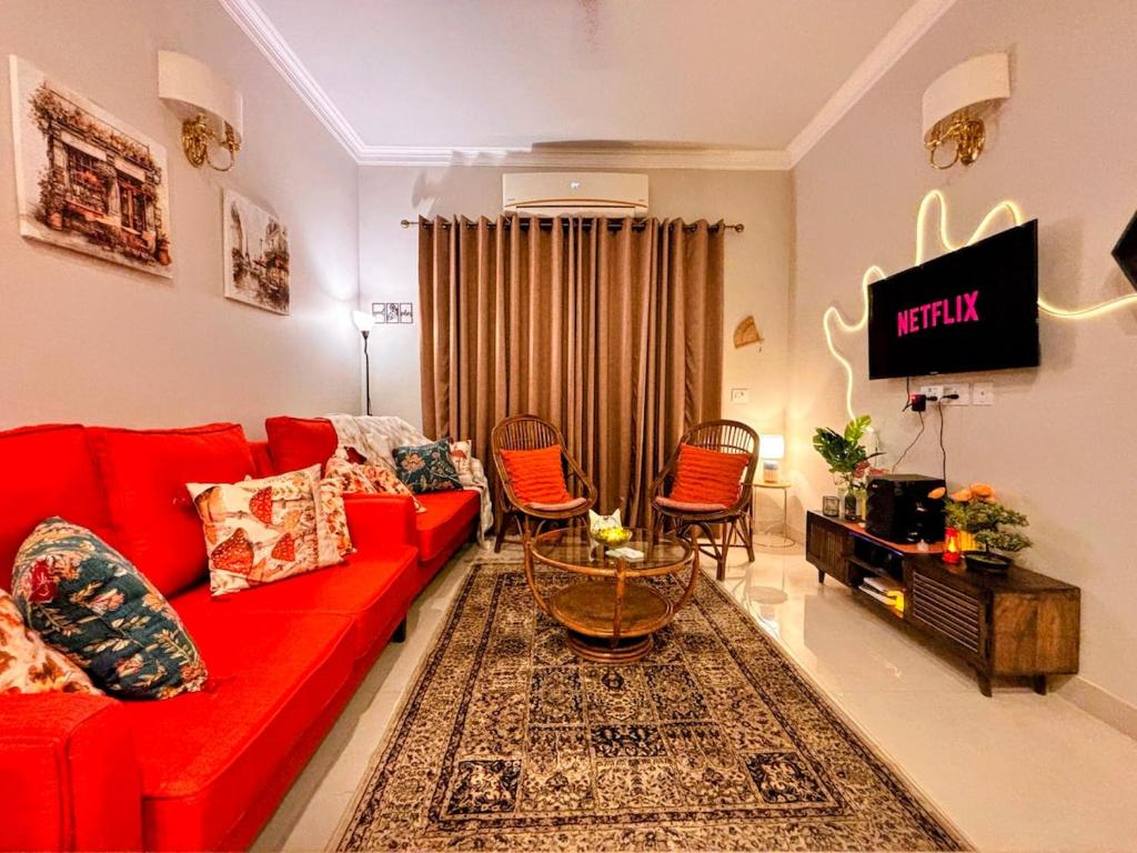 a living room with a red couch and chairs at Romantic Sky Studio with Pool by The Nook in Sohna