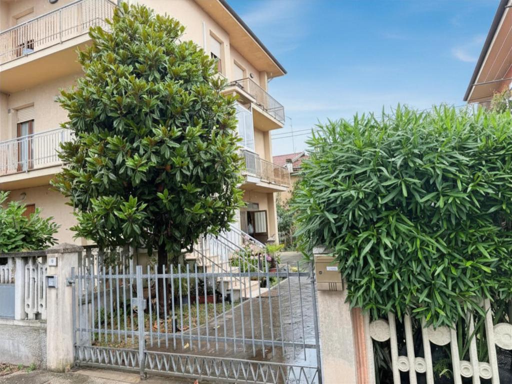 a fence with trees in front of a building at SE274 - Marotta, ampio quadrilocale con posto auto in Marotta