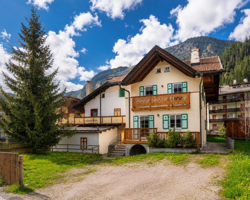 a house in the mountains with a tree at Casa Cesarina by AMA Val di Fassa in Canazei