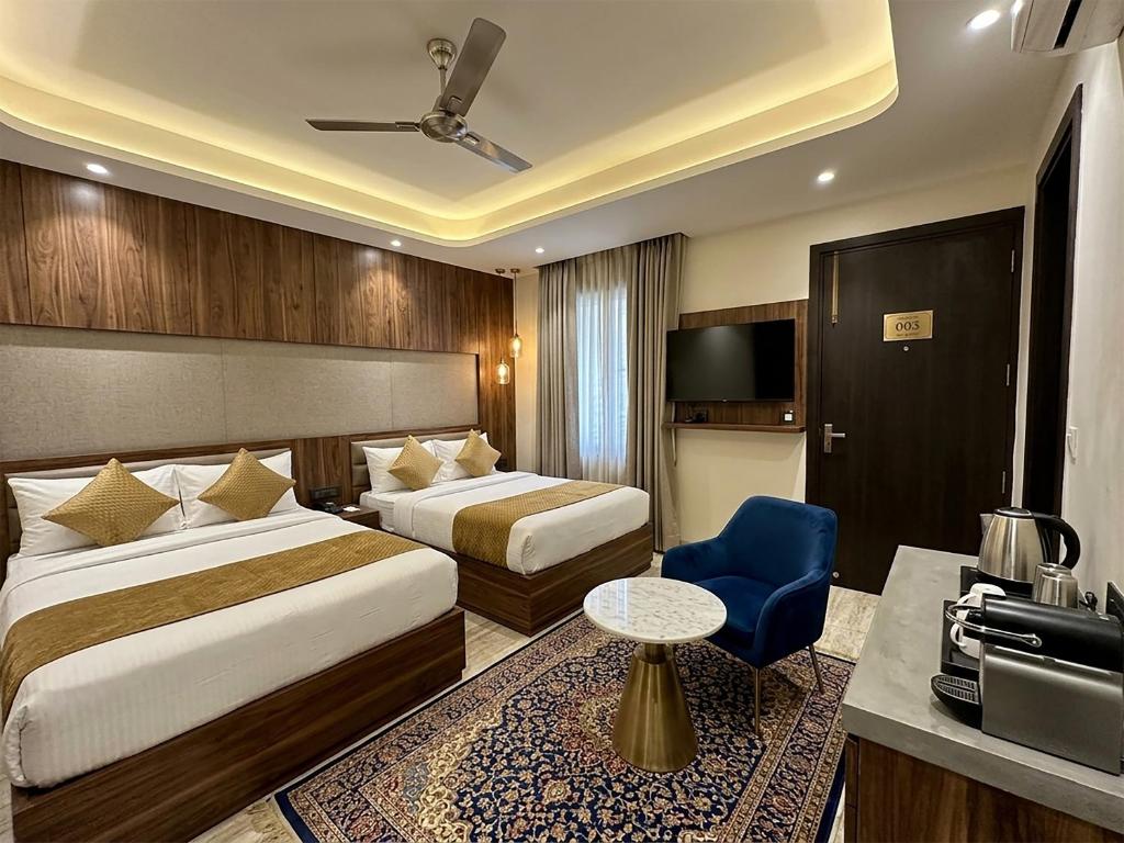 a hotel room with two beds and a blue chair at V Hotel Dev Residency Airport Pick up complimentary in New Delhi