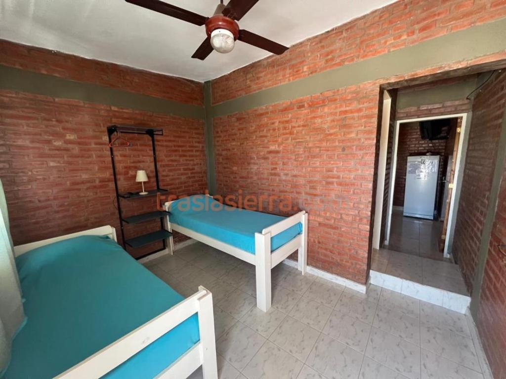 a bedroom with two beds and a brick wall at Mi Petaka in Villa Cura Brochero