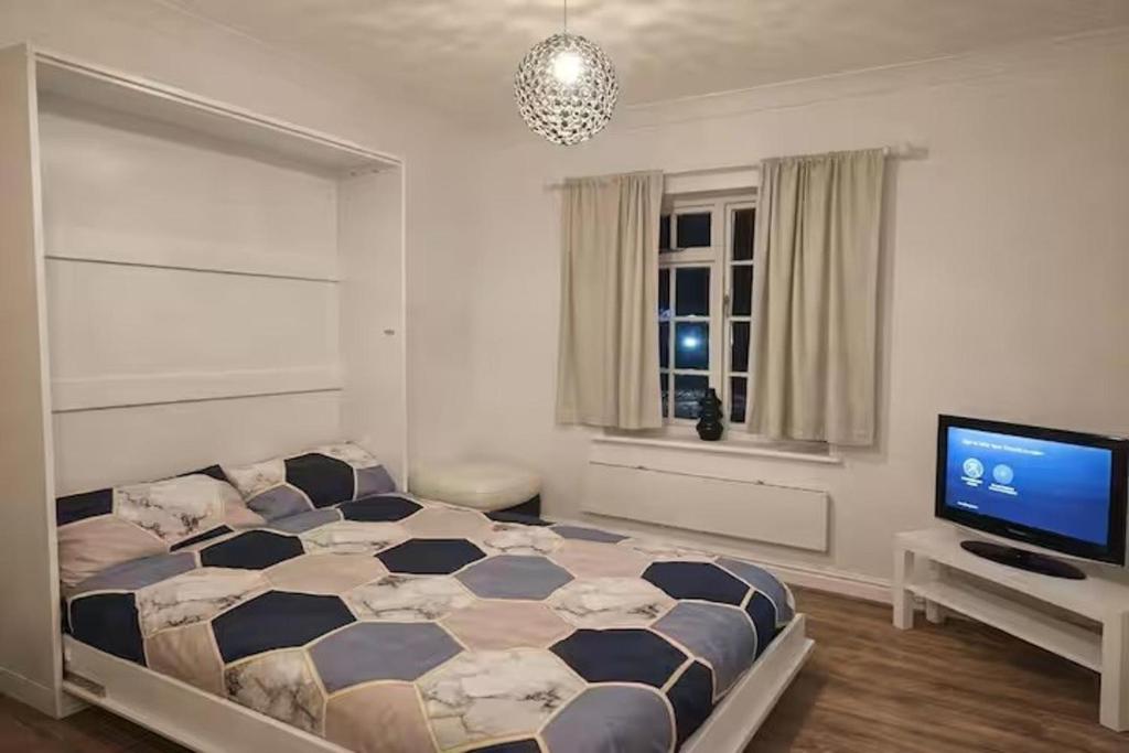 a bedroom with a bed and a flat screen tv at Newly Renovated Studio in Bishop's Stortford in Bishops Stortford