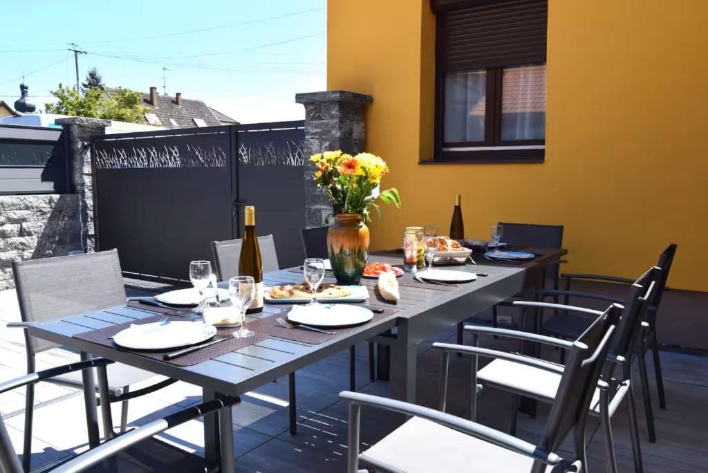 a wooden table with chairs and flowers on a patio at Le Courlis du Ried in Grussenheim