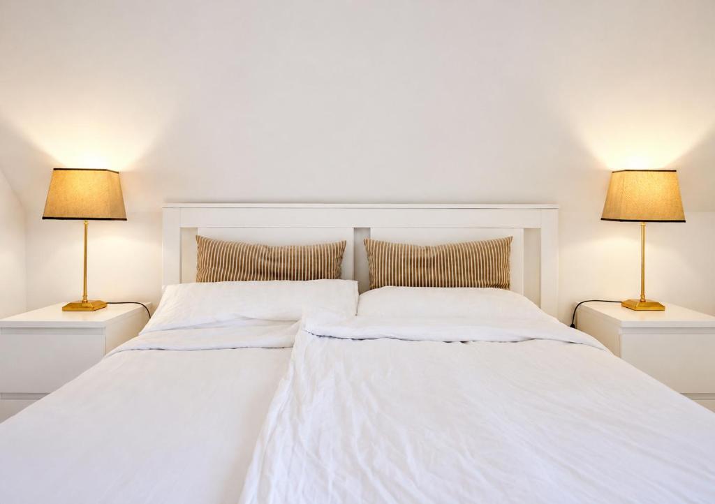 two beds in a white bedroom with two lamps at Trave Resort Ferienhaus in Schackendorf
