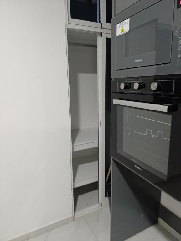 a kitchen with a microwave and a stove and a refrigerator at Apartamento Cidadela in Praia