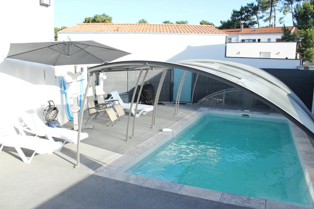 a patio with an umbrella and a swimming pool at L'Augustémile au bord de l'eau in La Tranche-sur-Mer
