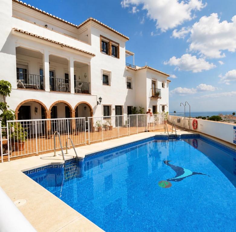 a villa with a swimming pool in front of a building at La vista encantada in Frigiliana