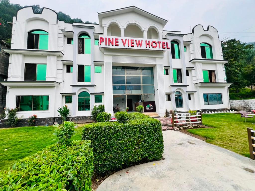 a white building with a sign that reads pine view hotel at Pine view Hotel Tranna Balakot in Hassa