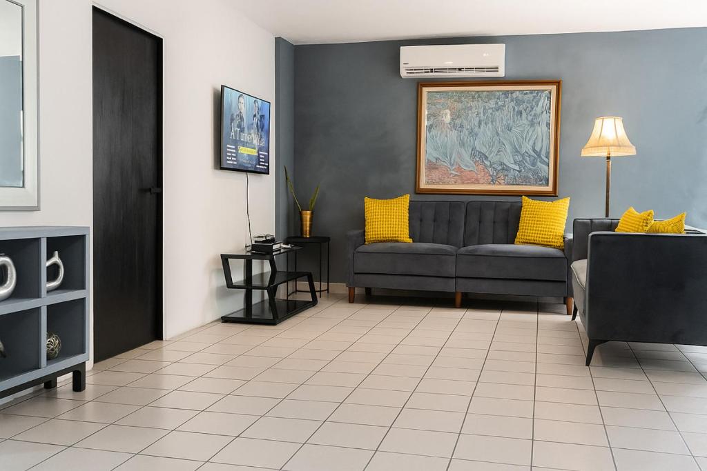 a living room with a gray couch and yellow pillows at OJAS Local Nest in San Juan