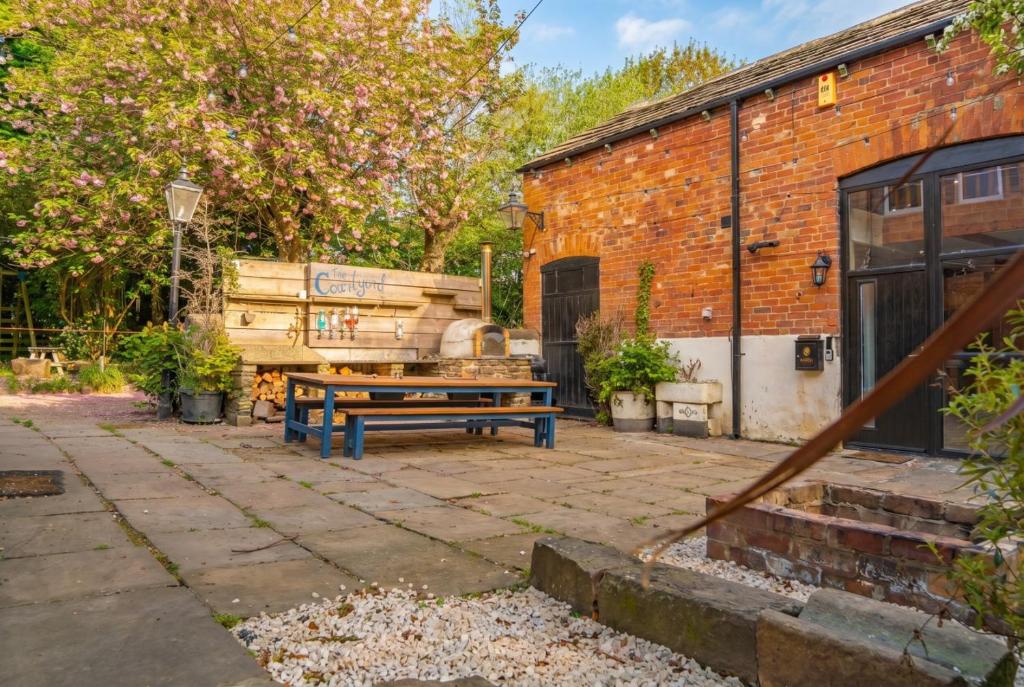 a patio with a picnic table and a brick building at Luxury Escape with Cinema, Pool Table & Darts in Leeds