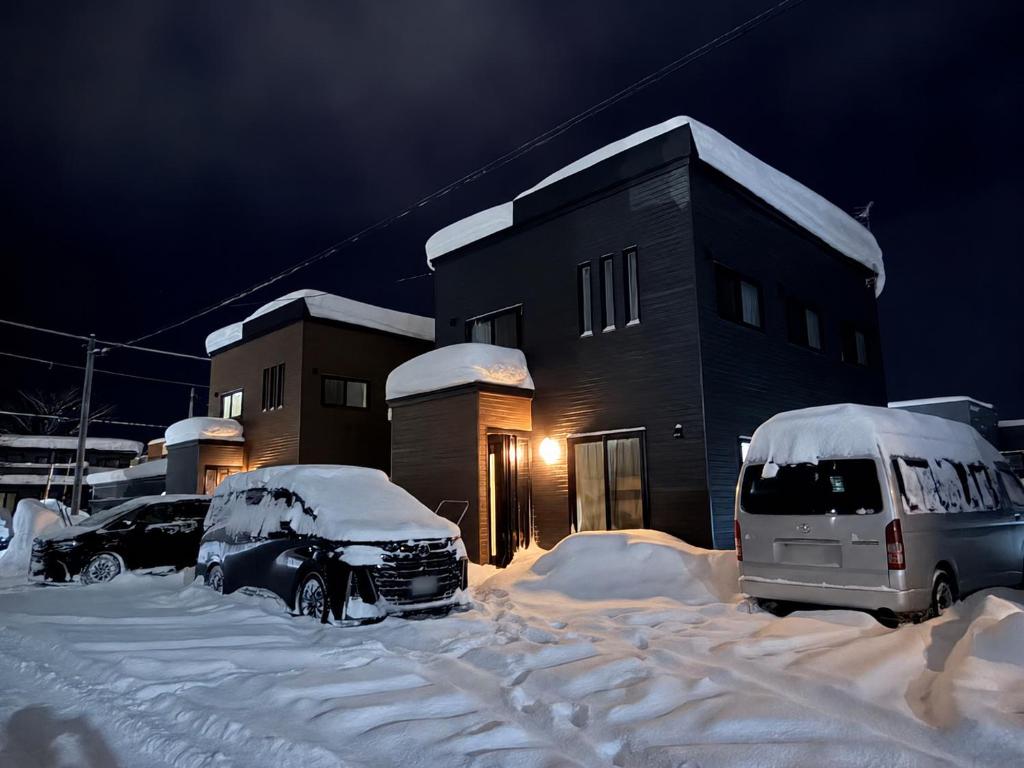 two cars parked in a snow covered parking lot in front of a building at 雪宿snow iin in Kutchan
