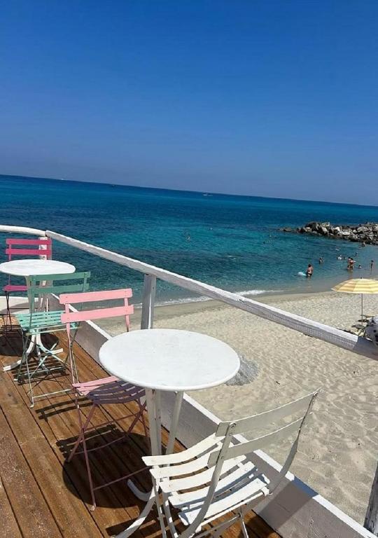 a deck with tables and chairs on the beach at Residenza Gherly in Capo Vaticano