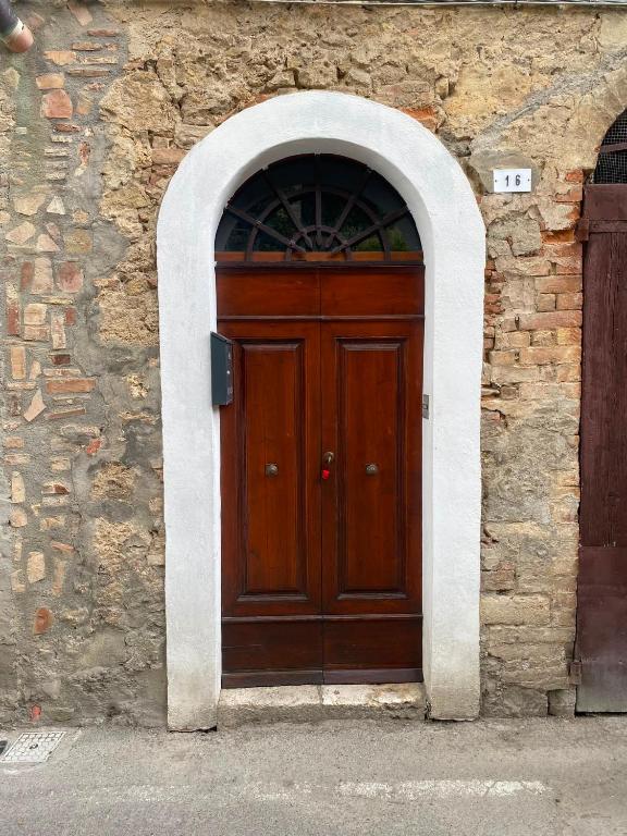 a wooden door in a stone building with an arch at La chiesina delle conce in Sarteano
