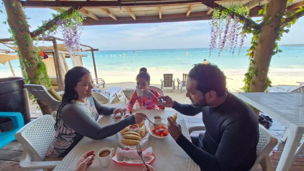 a family eating food at a table on the beach at Cabañas Palos Locos in Barú