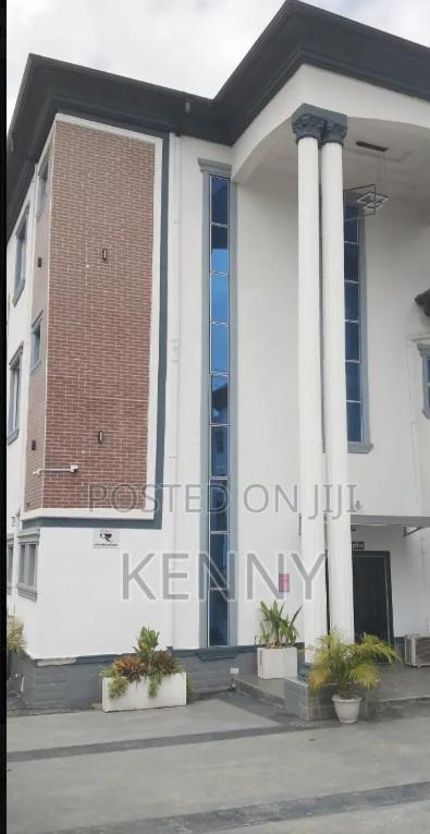 a white building with columns and plants in front of it at S&B Hotel in Agege