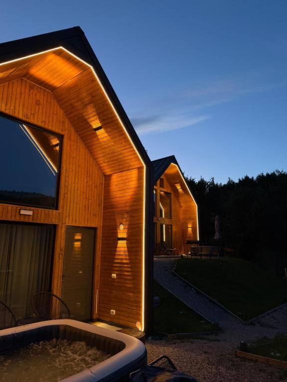 a large wooden house with a tub in front of it at Kolibe Doftana in Trăisteni