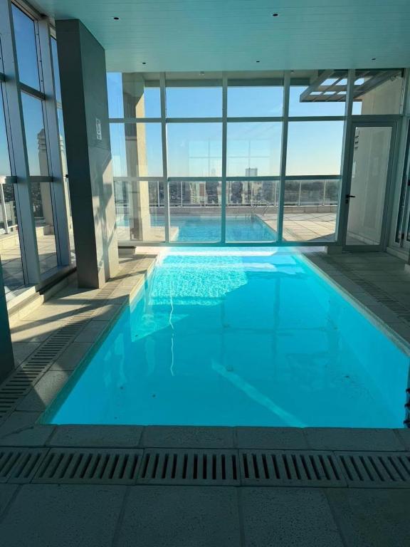 a large blue swimming pool in a building with windows at Departamento Excelente Ubicación - Torre Fenix in Santa Fe